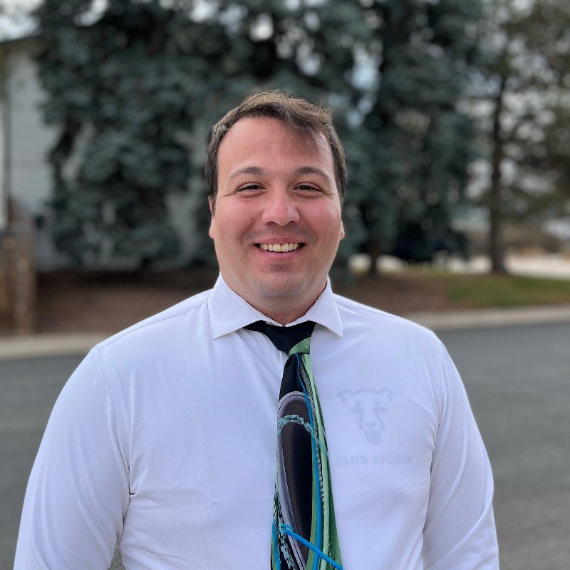 portrait Picture of the Owner Noah Holt, In a white dress shirt and a black and green tie on.